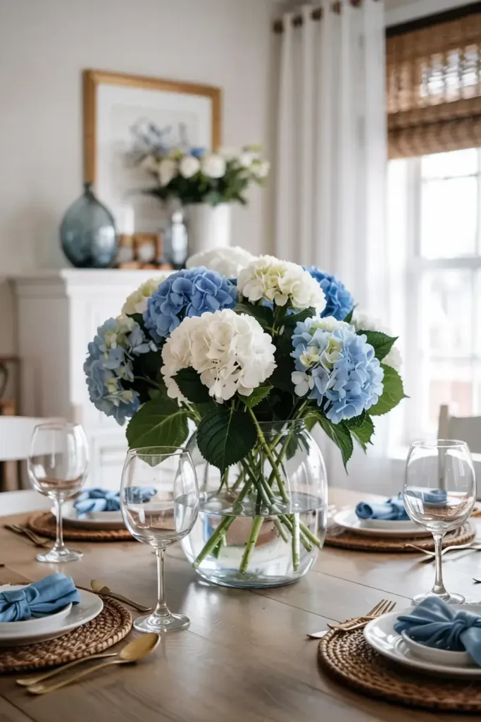 A dining table set with a large vase of blue and white hydrangeas as the centerpiece.